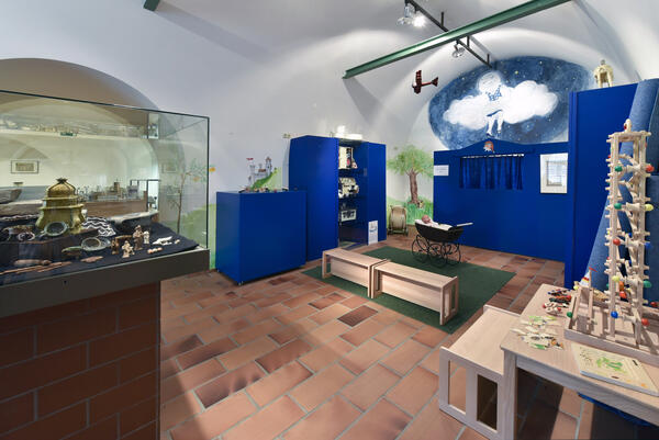 Bild vergrößern: Spielzeugmuseum mit Puppenwagen und blauem Marionettentheater