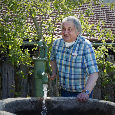 Bild vergrößern: Mann bedient einen Brunnen