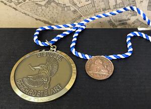 Bild vergrößern: Medaille an blau-weißem Band mit Kupfermünze